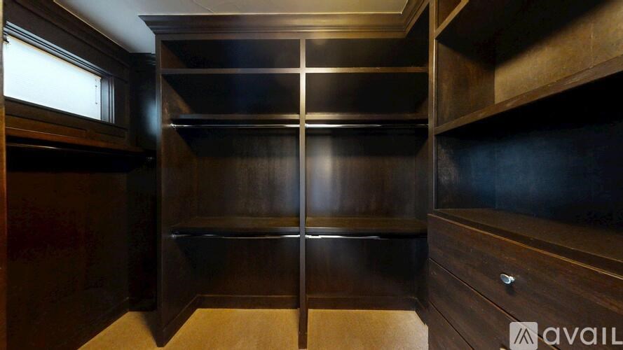A wooden pantry with a window and shelves.