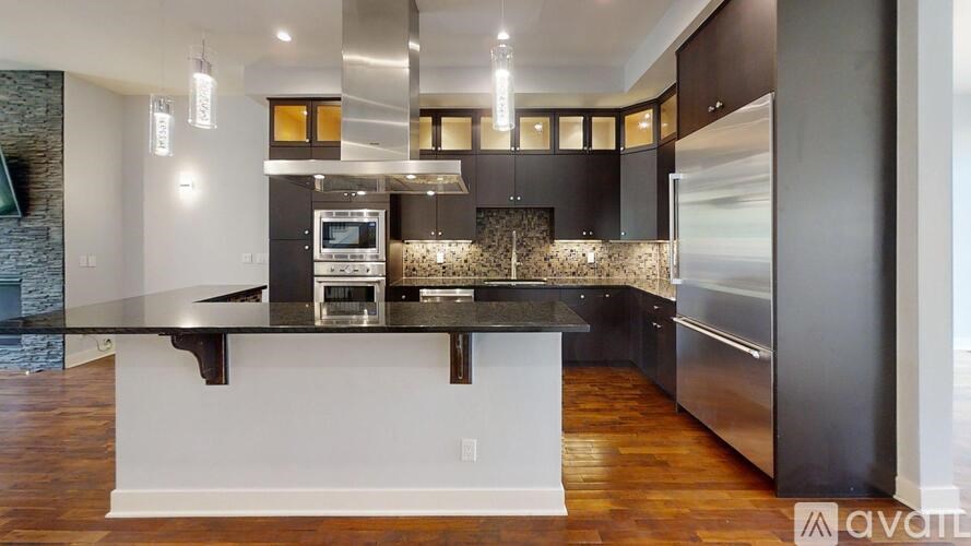 A modern kitchen with a stone wall and wooden floors.