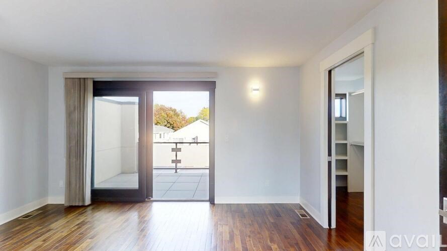 A room with wooden floors and a sliding glass door leading to a balcony.