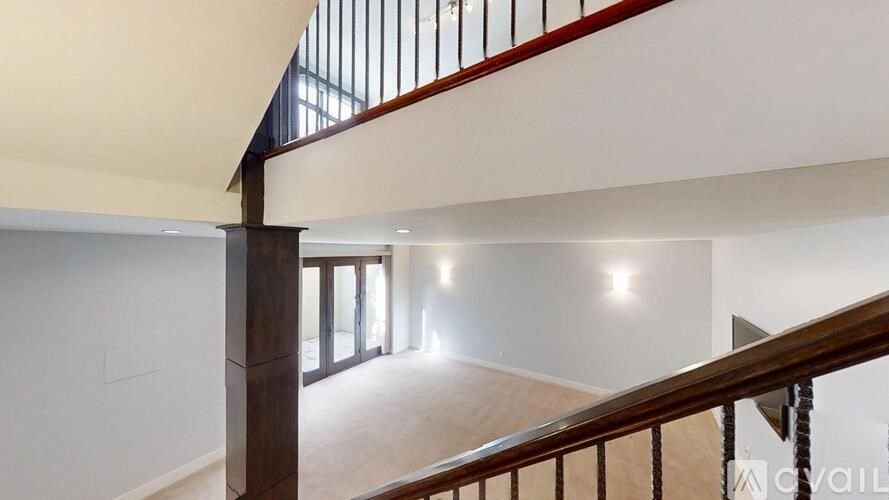 A staircase with a wooden handrail and a white wall on the left side.