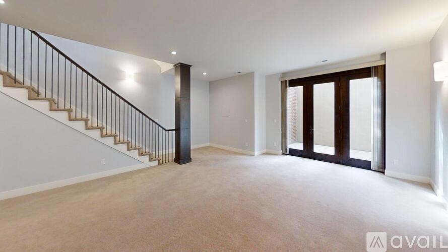 A spacious room with a staircase and a door leading to another room.