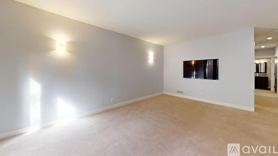 A spacious room with a large window on the left side and a flat screen TV mounted on the wall.