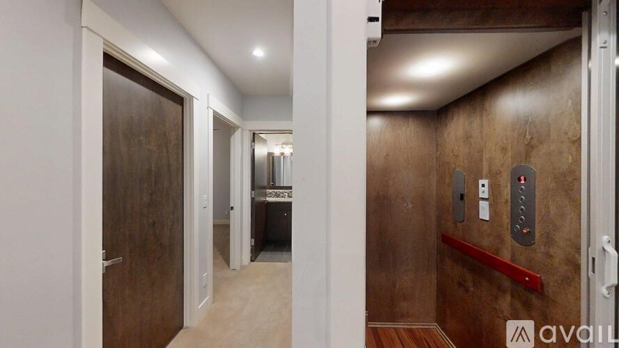 A hallway with a brown door and a red handle.