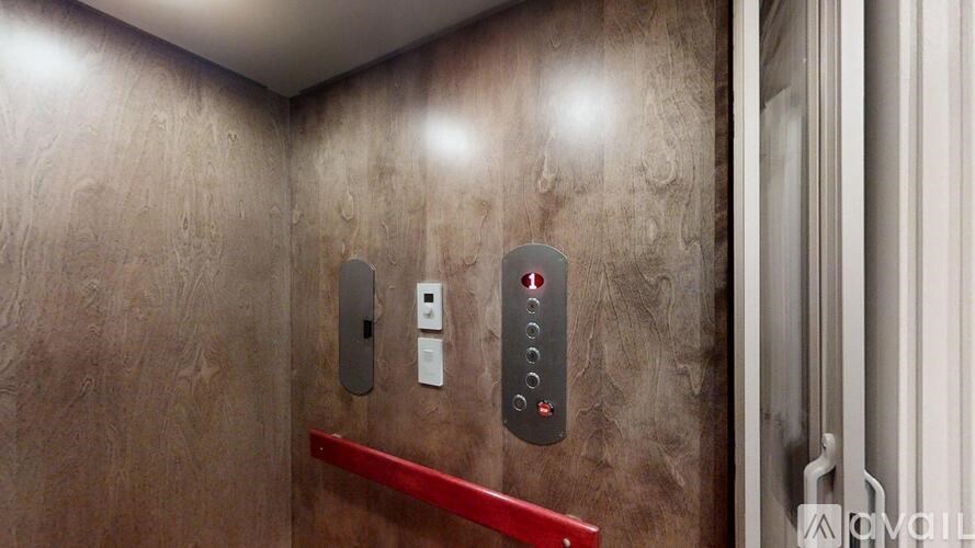 A red button is located on a wall next to a door.