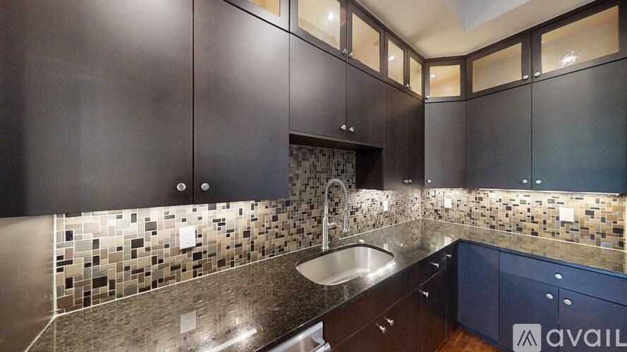 A kitchen with dark wood cabinets and a mosaic tile backsplash.
