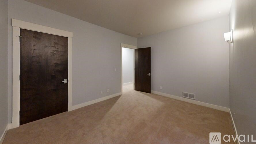 A room with a brown carpet and a wooden door.