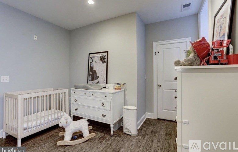 A baby room with a white crib, a white dresser, a white changing table and a white rocking horse.