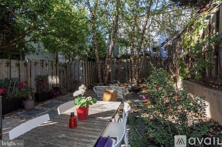 A backyard with a table and chairs surrounded by a fence and trees.