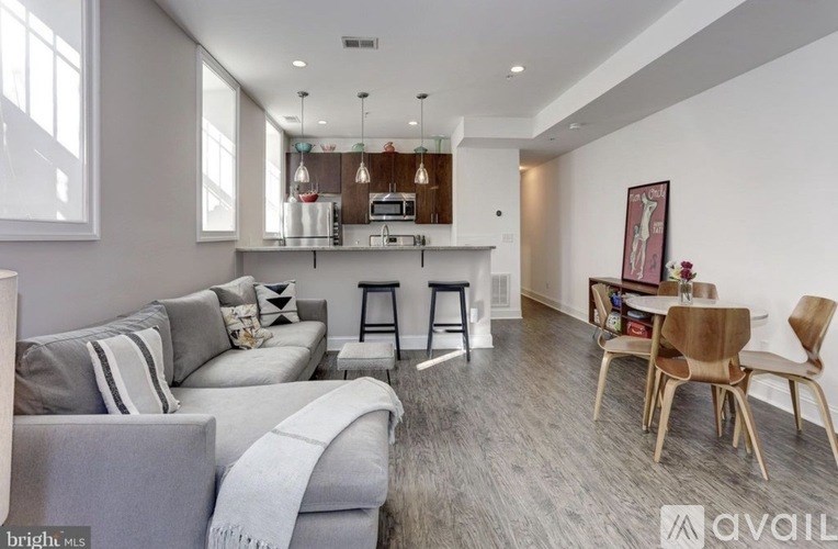 A modern living room with grey couches and wooden chairs.