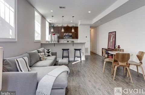 A modern living room with grey couches and wooden chairs.