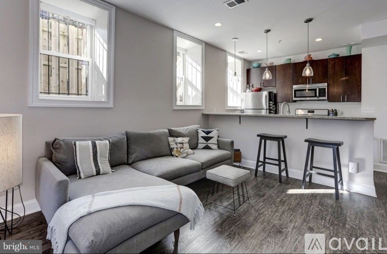 A modern living room with a grey couch and a bar area.