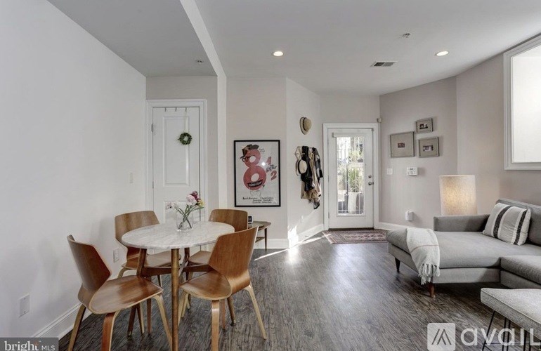 A well-lit living room with a dining table and chairs.