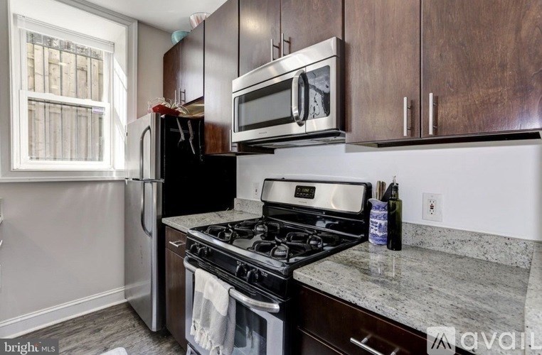 A kitchen with a black fridge, stove, and microwave.
