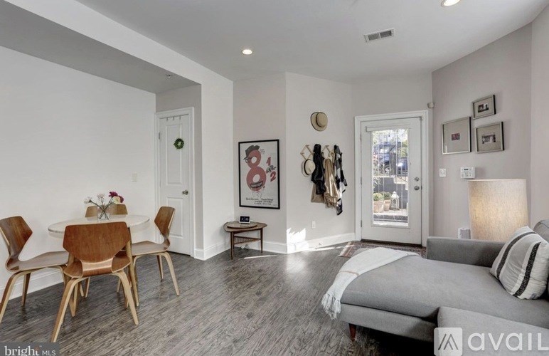 A living room with a grey couch and a wooden dining table with chairs.