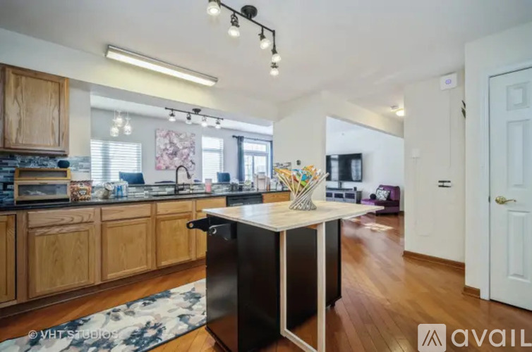 A kitchen with wooden cabinets and a black island.