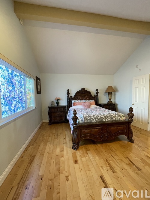 A bedroom with a large bed and wooden floors.