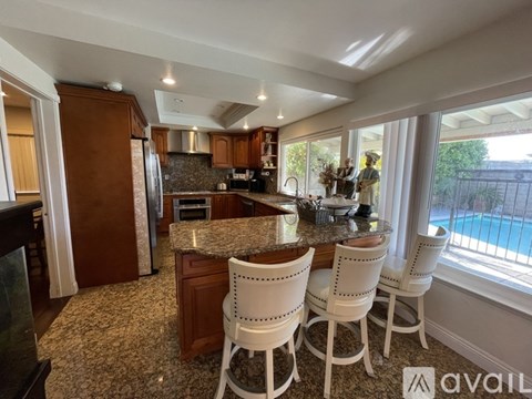 A kitchen with white chairs and a granite counter.