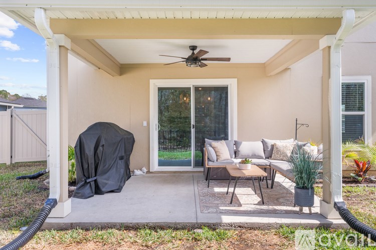 A covered outdoor patio area with a black umbrella and a fan.