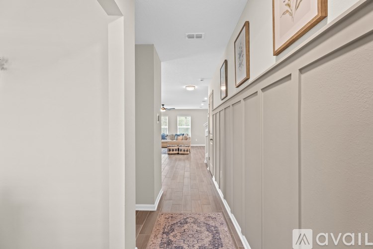 A hallway with a rug on the floor and pictures on the wall.