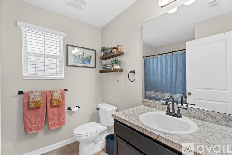 A bathroom with a toilet, sink, and a window.