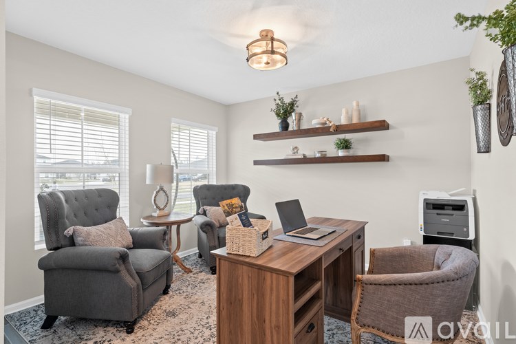 A well-lit room with a desk, chairs, and shelves.