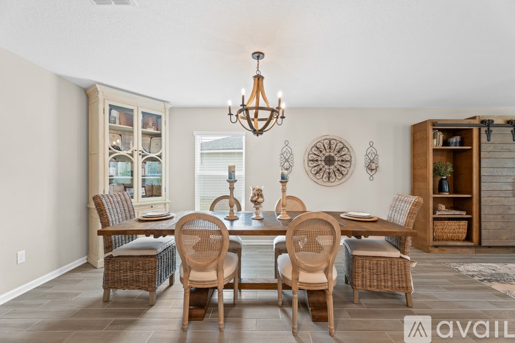 A dining room with a table set for four and a chandelier hanging from the ceiling.