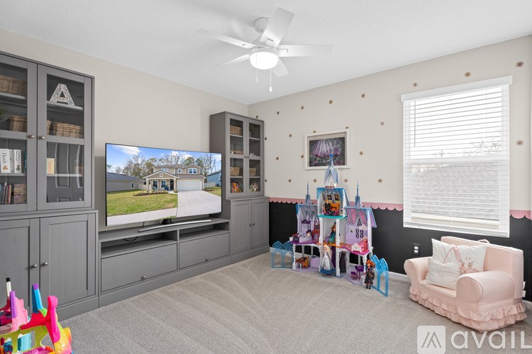 A living room with a television, a chair, and a play area for children.