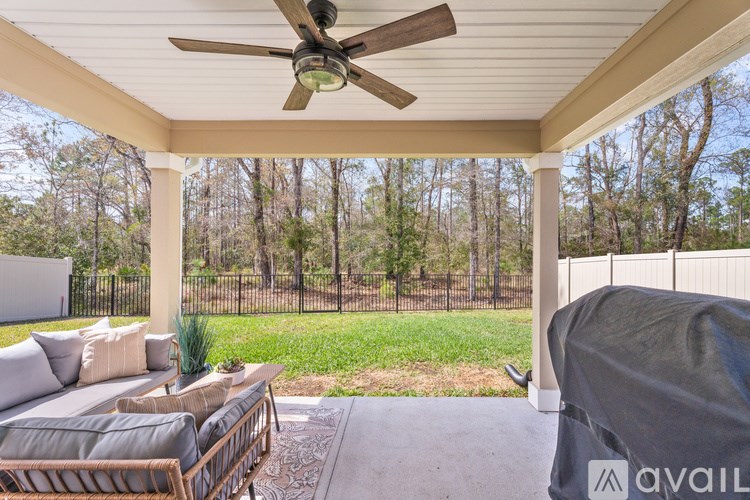 A patio with a couch, chairs, and a ceiling fan.