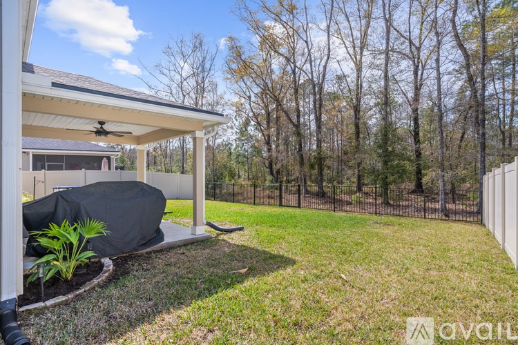 A covered patio area with a black couch and a fan.