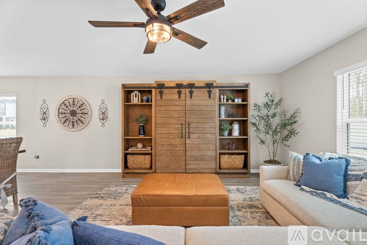 A living room with a ceiling fan, a couch, and a wooden cabinet.