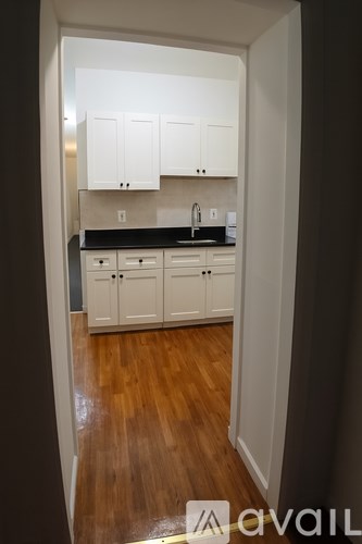 A kitchen with white cabinets and a black countertop.
