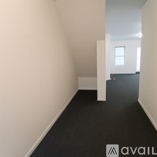 A hallway with a carpeted floor and white walls.