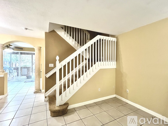 A staircase with a white railing and a cat tree in the bottom left corner.