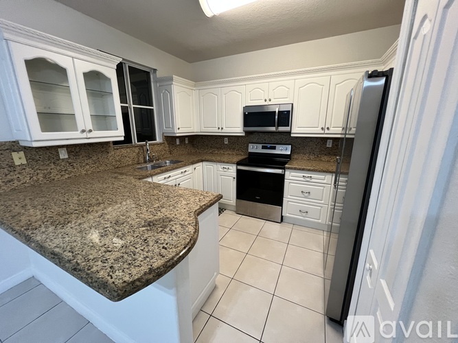 A kitchen with a stainless steel refrigerator and white cabinets.