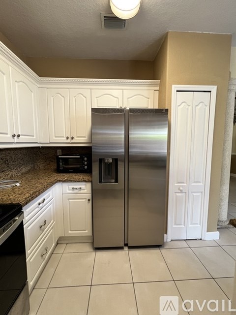 A kitchen with a stainless steel refrigerator and white cabinets.