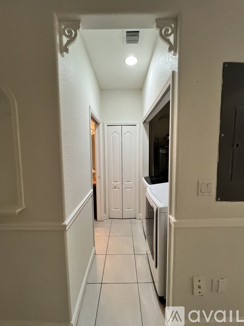 A hallway with a chandelier and a carpeted floor.