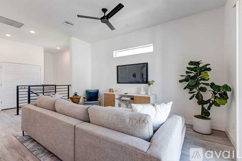 A living room with a grey sofa and a television on the wall.