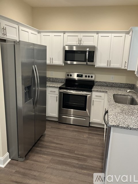 A kitchen with a stainless steel refrigerator, microwave, oven, and cabinets.