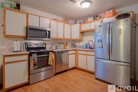 A kitchen with a stainless steel refrigerator and wooden cabinets.