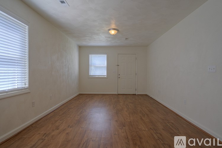 A room with wooden floors and a window with blinds.