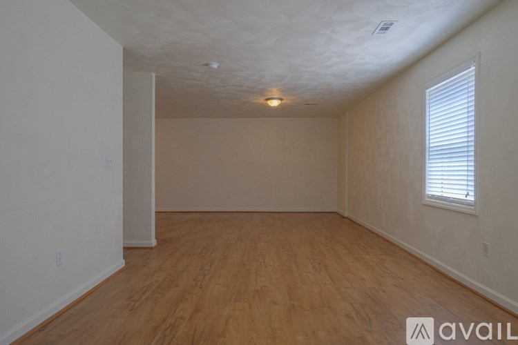 A room with wooden flooring and a window with blinds.