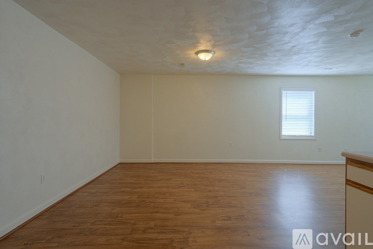 A room with wooden flooring and a window with blinds.
