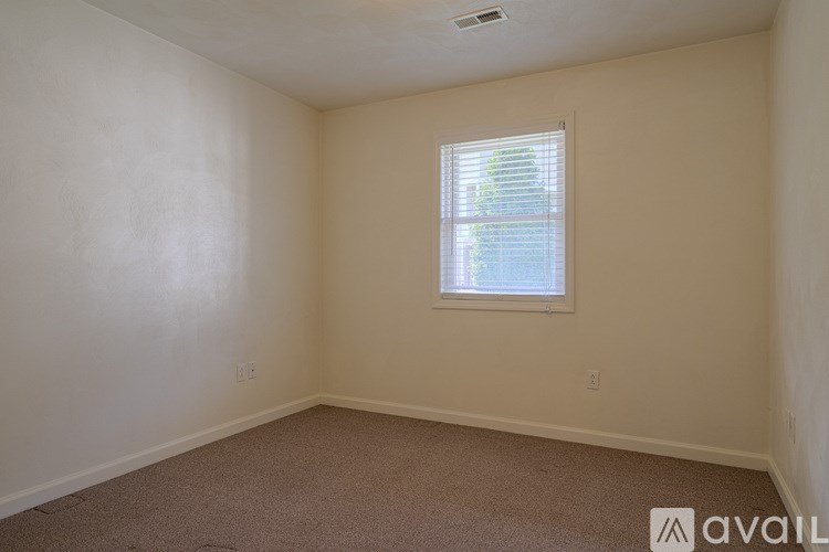 A room with a window and carpeted floor.