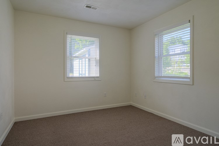 A room with two windows and carpeted floor.