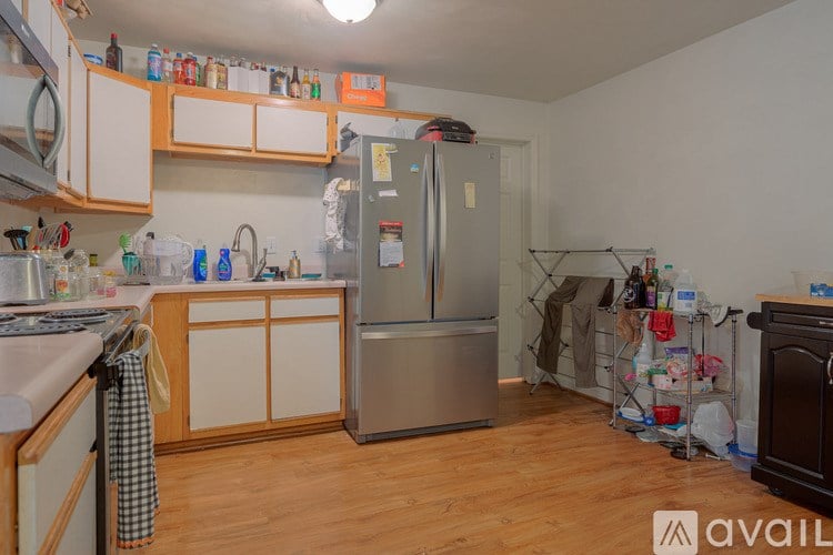 A kitchen with wooden floors and a refrigerator in the middle.