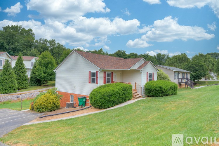 A house with a red roof and white walls is surrounded by greenery.