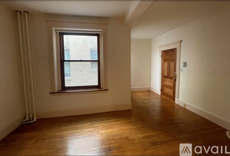 A room with wooden floors and a window with white curtains.