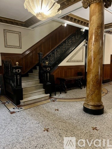 A staircase with a wooden banister and a marble column.