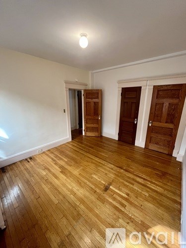 A room with wooden floors and two doors.