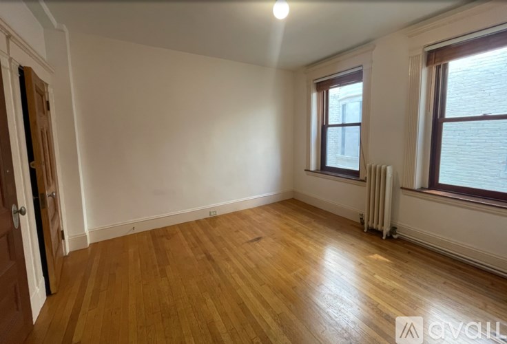 A room with wooden flooring and a window with a white frame.